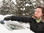 woman cleaning snow off of car